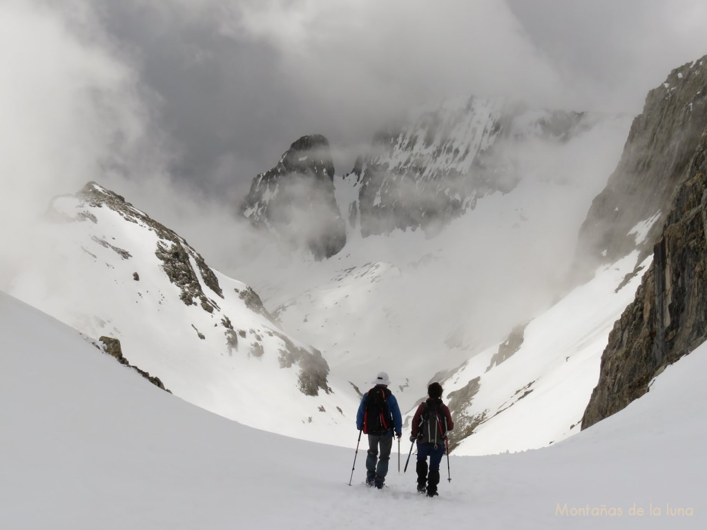 Lea y Xita bajando por la Canal Fonda, enfrente las Crestas del Forcau entre nubes