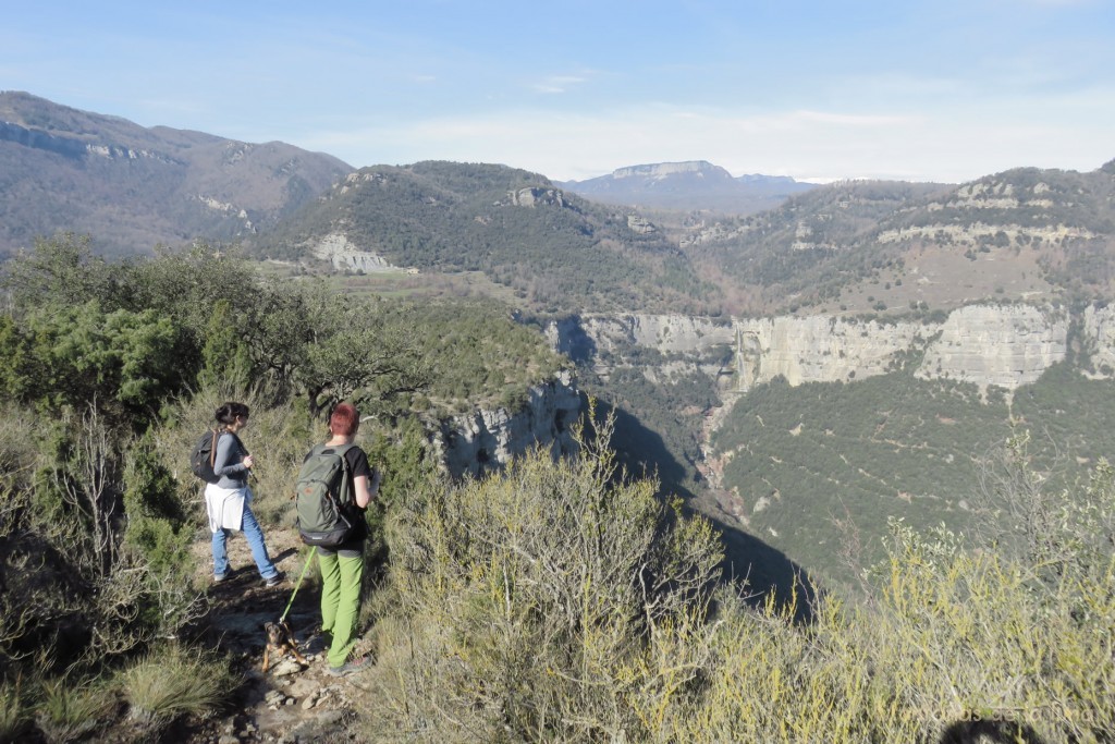 Agnes y su amiga caminando por el Pla Xic de vuelt, en el centro, entre las paredes, el Salt de Sallent, al fondo arriba la Sierra de Cabrera