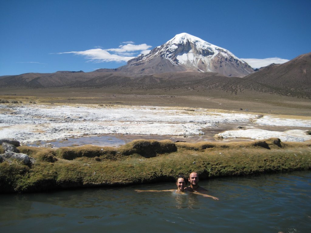 Javi y Zaida bañándose en las Aguas Termales Colchapata en la Comunidad Jila Uta Manasaya, con el Sajama al fondo