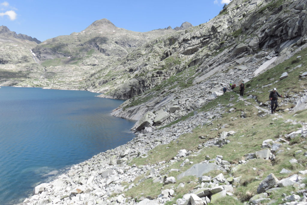 Delante Josep en el recorrido por la orilla este del Ibón de Bachimaña Superior. En el centro de la imagen se observan las cornisas de roca, lugar del paso con cadena