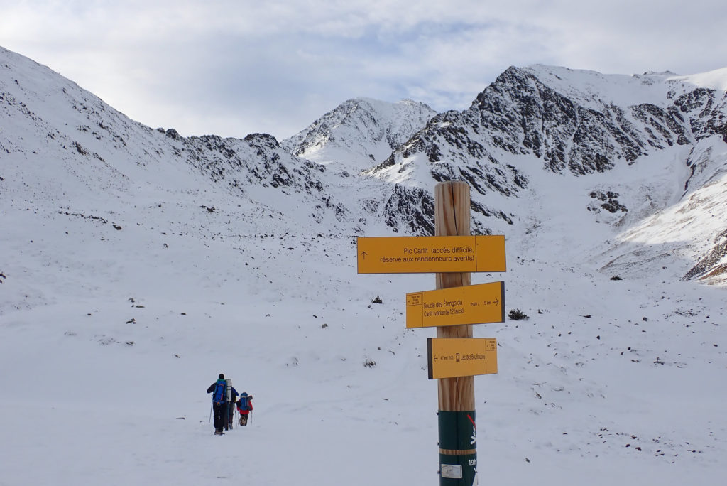 Poste indicador de recorridos con el Carlit al fondo, con el Carlit de Baix a su derecha